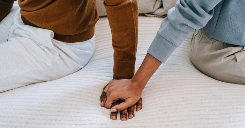 https://www.pexels.com/photo/crop-unrecognizable-black-couple-holding-hands-on-bed-5700177/
