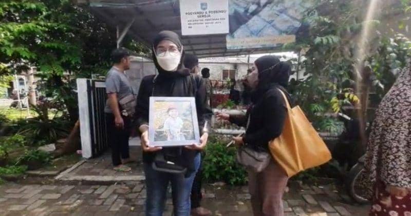Ibu sambung korban memegang foto korban saat akan dimakamkan - IDN Times/Dicky