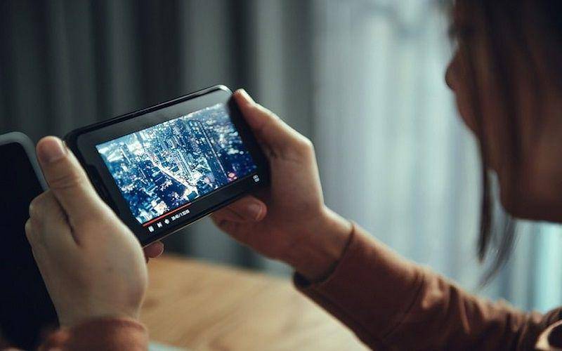 ilustrasi seorang perempuan sedang asyik menonton film di smartphone (freepik.com/oatawa)