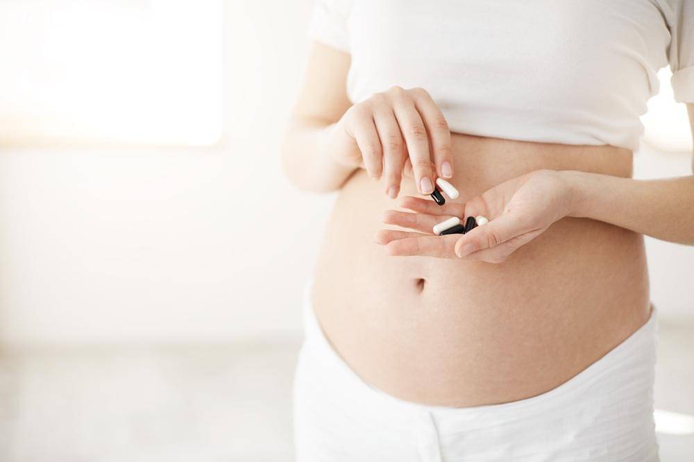 closeup-pregnant-soon-be-mother-holding-pills-medications-vitamins-healthy-motherhood-concept.jpg