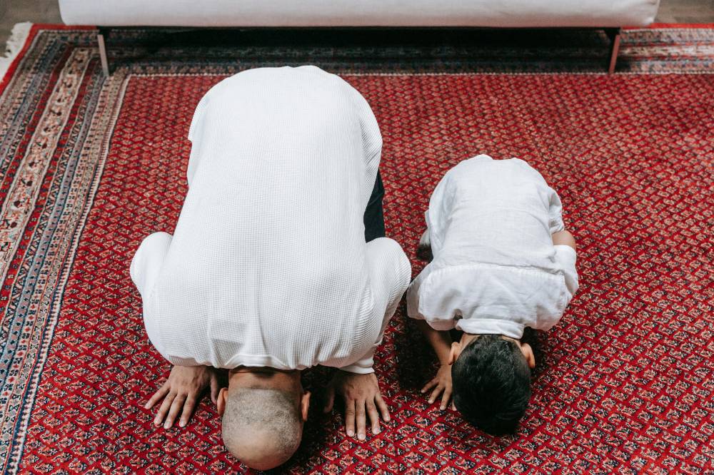 Papa dan anak sedang salat berjamaah