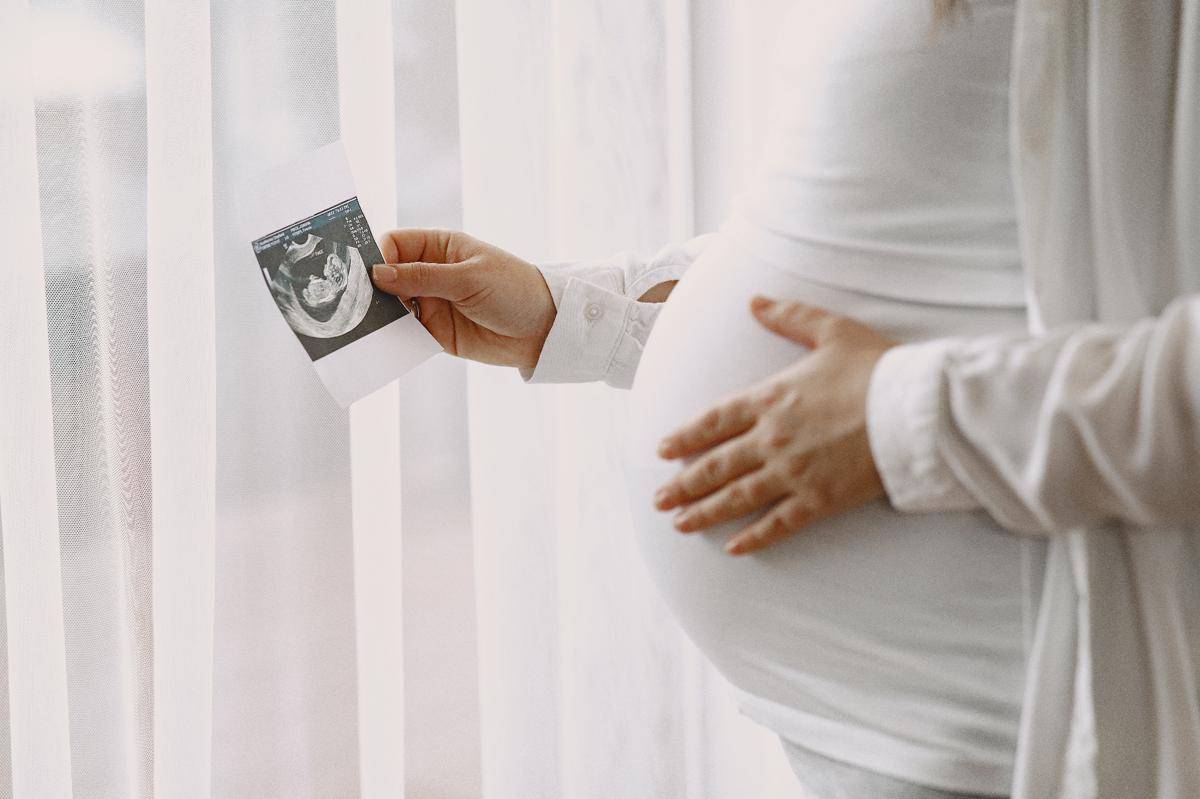 pregnant-woman-standing-by-window-looking-photo.jpg