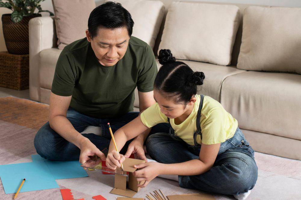 Ayah dan anak sedang membuat rumah kardus