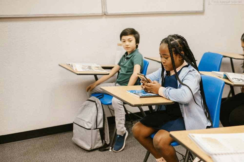Anak membaca chat di ponsel ketika sekolah