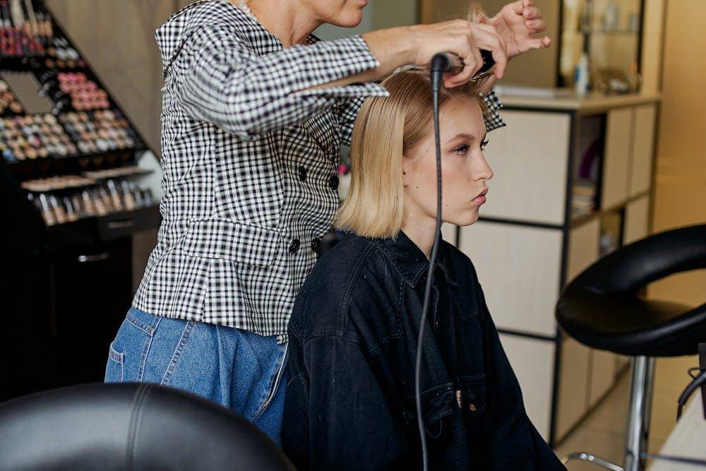 hairstylist straightening hair of woman with iron