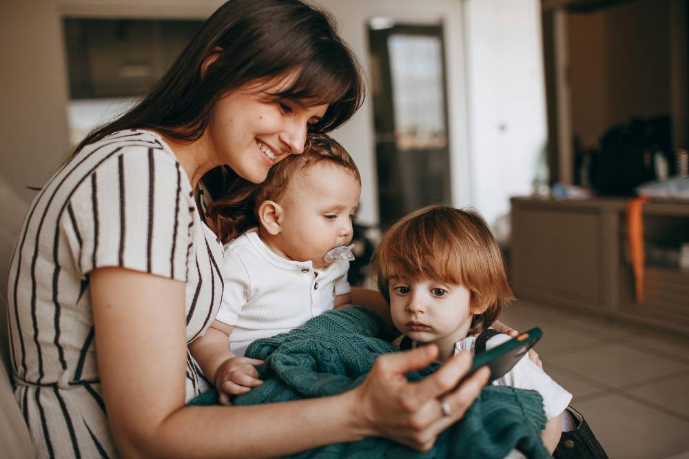 Anak bermain ponsel bersama ibu