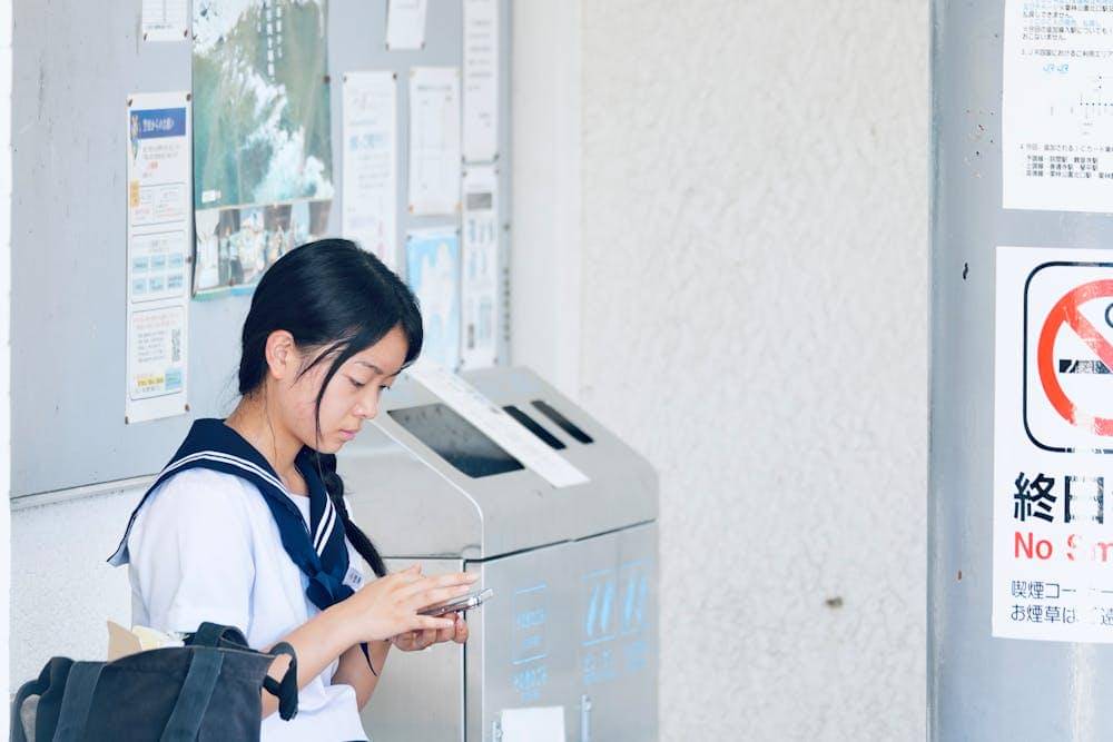 japanese schoolgirl in uniform using smartphone