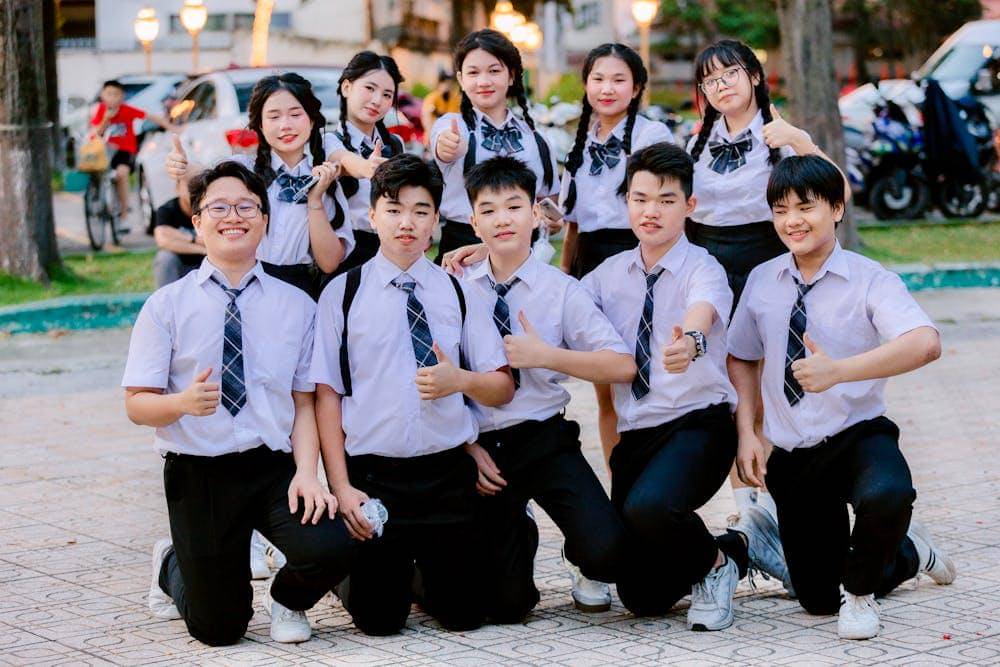 group of students celebrating outdoors in uniform