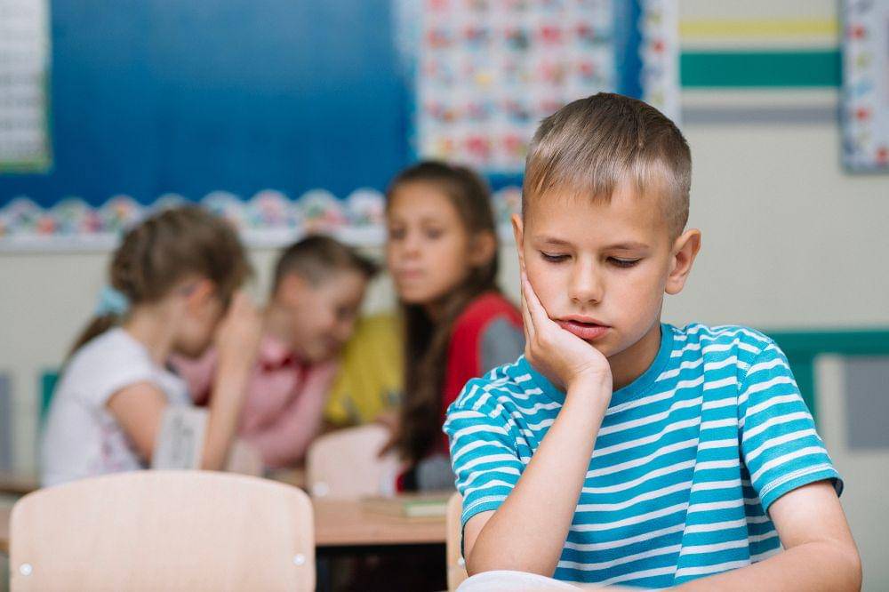 Anak laki-laki menjauh dari teman-teman kelasnya