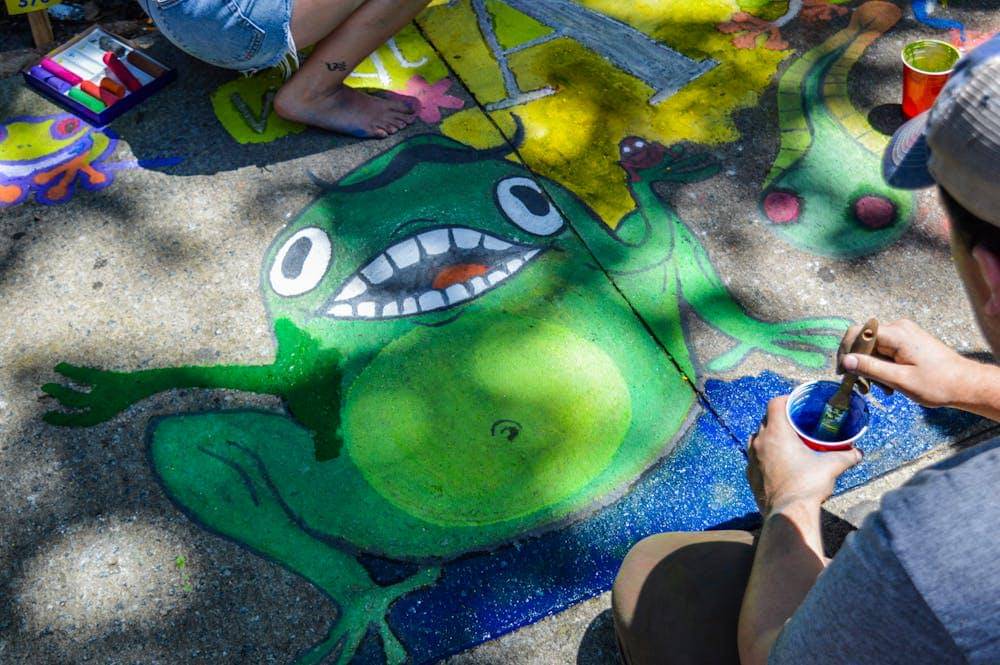 man painting green frog on ground