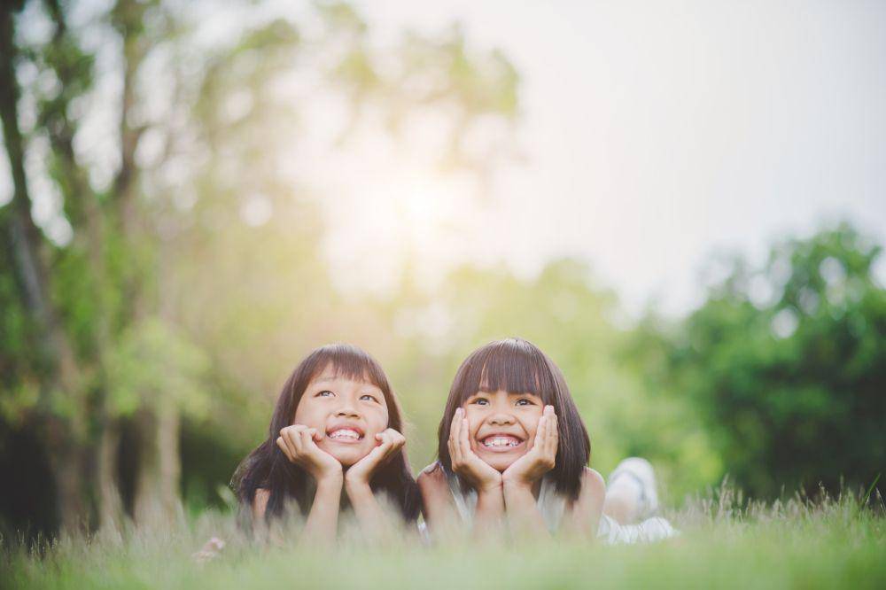 Little girl with friend lying comfortably on the grass