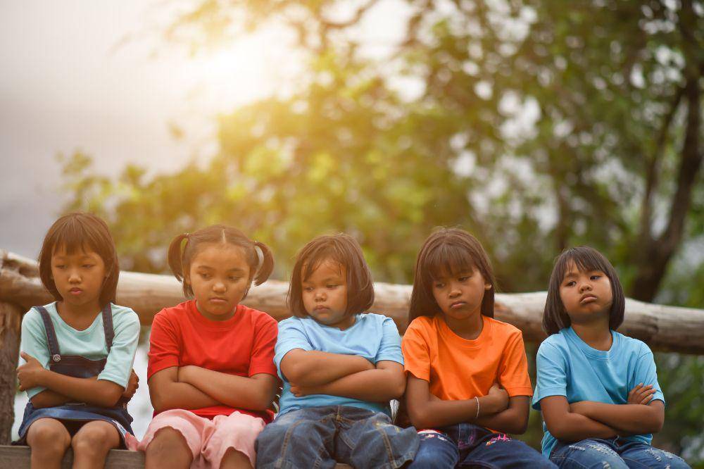 Group of sad kids sitting on the park