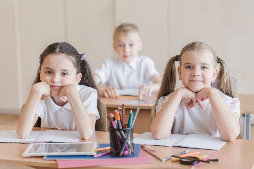 dua anak perempuan duduk di kelas
