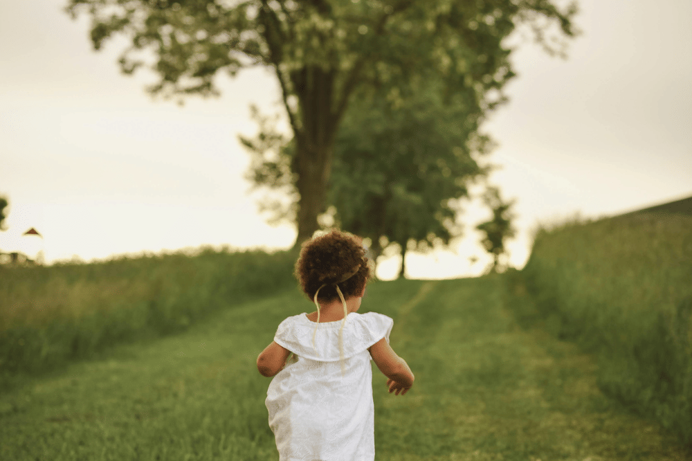 Anak toddler berlari di tanah hijau