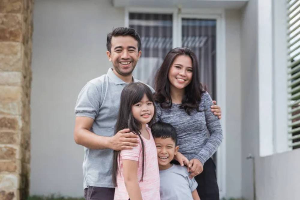 Keluarga dengan dua anak di depan rumah