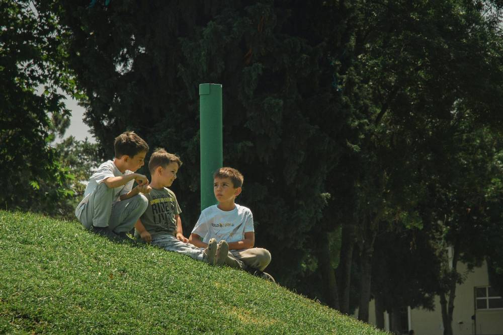 Tiga anak laki-laki duduk di taman