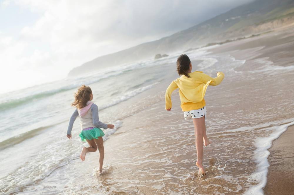 Dua anak perempuan berlari di pantai