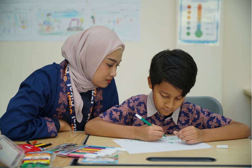Guru memperhatikan anak menulis