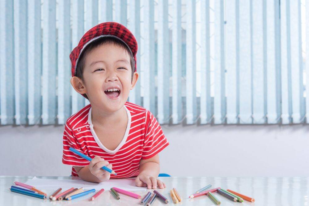 Cute boy draws with color pencils
