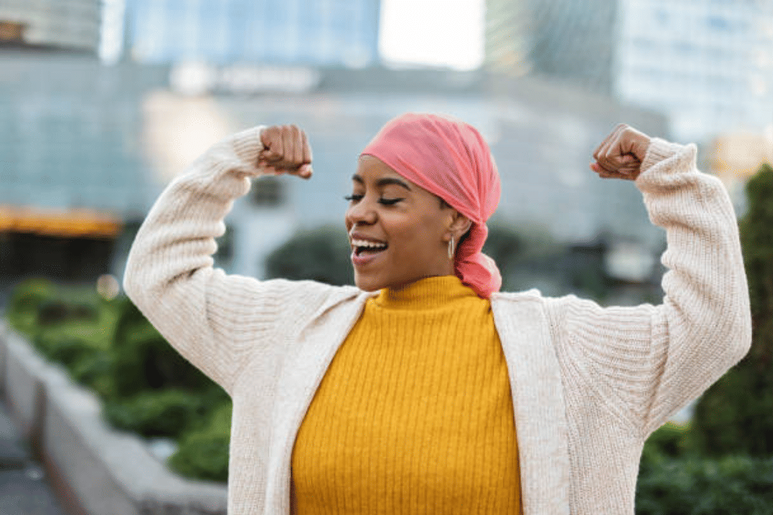 Wanita Latina, berjuang melawan kanker payudara, mengenakan syal merah muda, dan mengepalkan tangannya sebagai pejuang yang selamat. (istockphoto.com/Jose carlos Cerdeno)