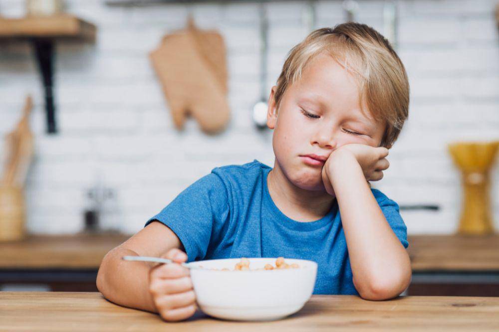 Front view tired boy trying to eat his cereals