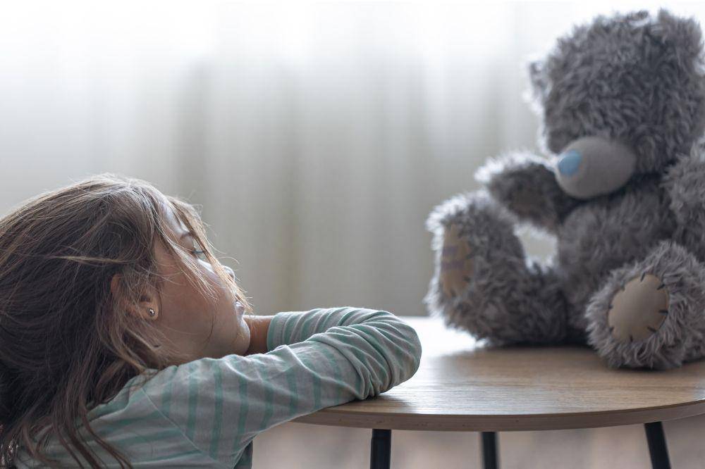Little girl looks at her teddy bear
