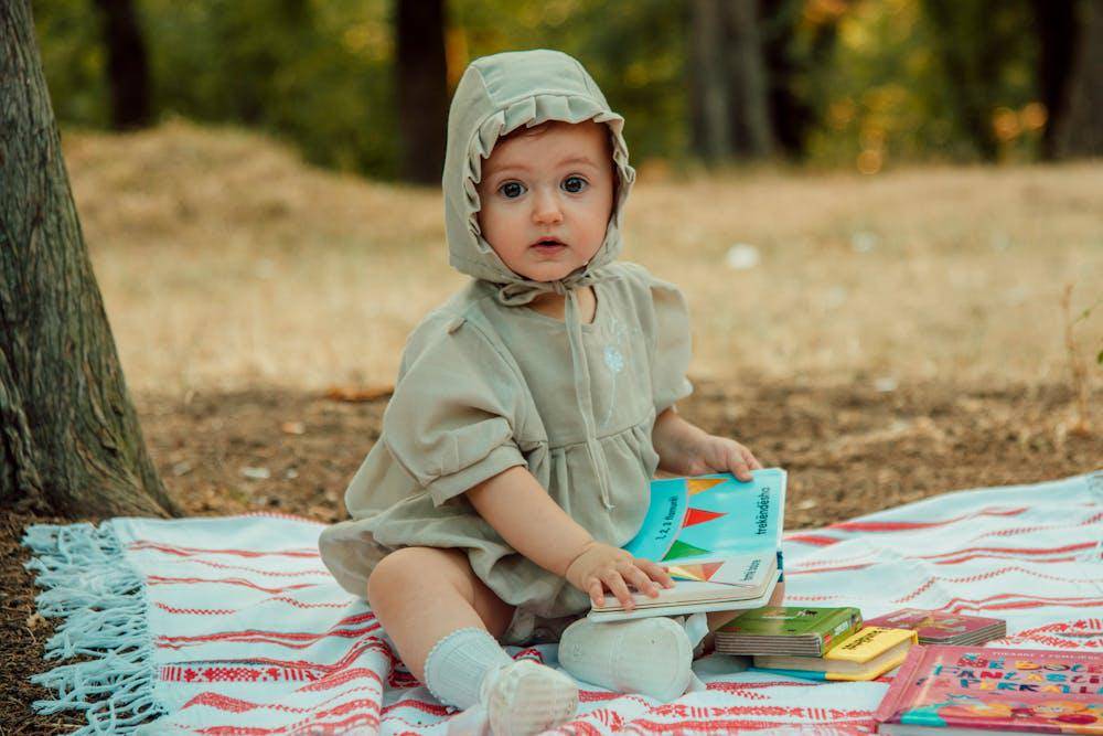 boy in hoodie sitting on picnic blanket with books