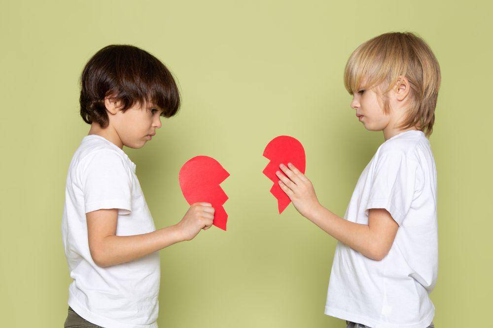 two boys holding red teared heart