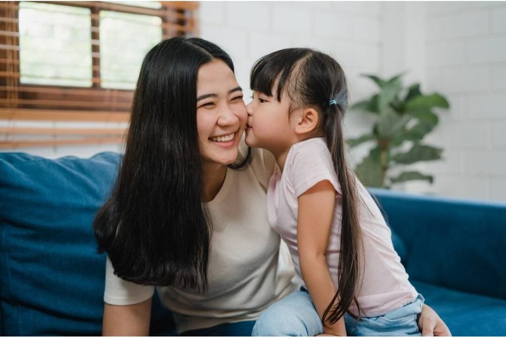 Anak mencium pipi ibu di rumah