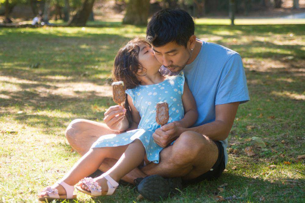 father and daughter resting with ice cream in park