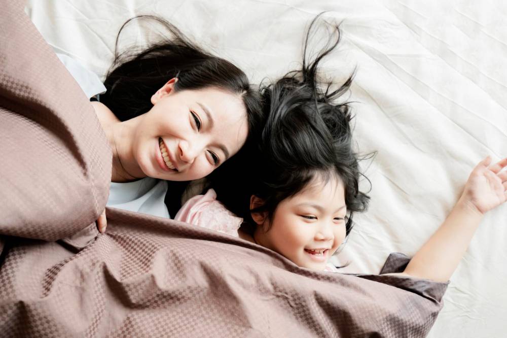 Ibu dan anak berbincang di kasur