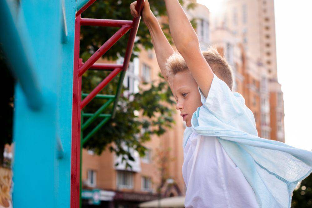 boy hanging on a bar with his hands
