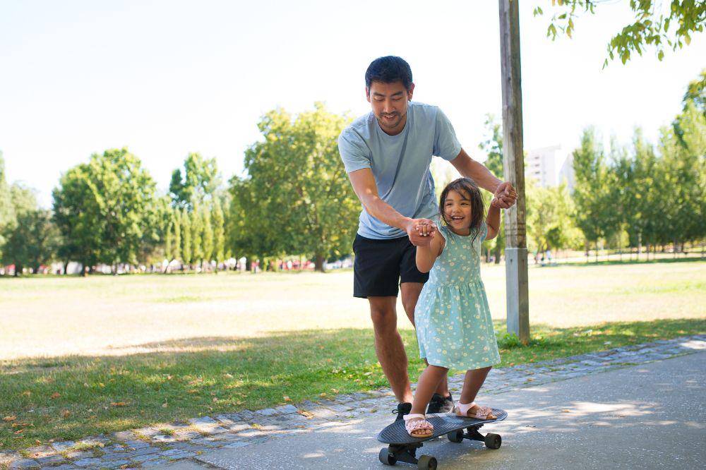dad and little girl training to skateboard