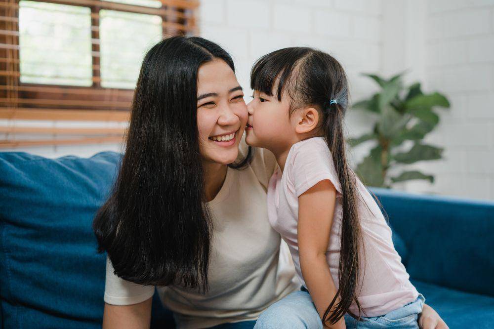 mom and daughter embracing kissing on cheek