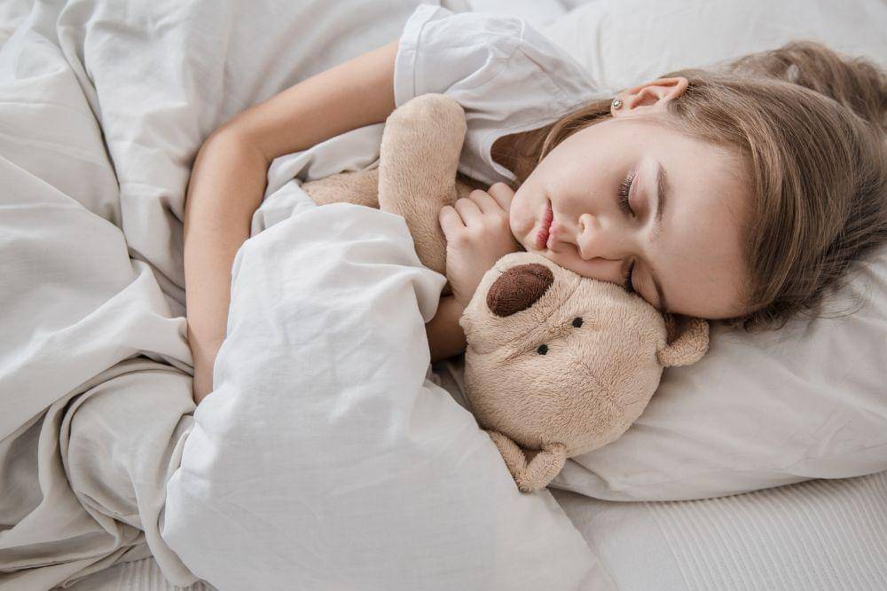 little girl in bed with soft toy