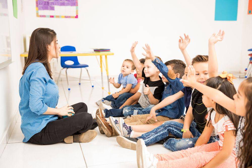 preschool students raising their hands