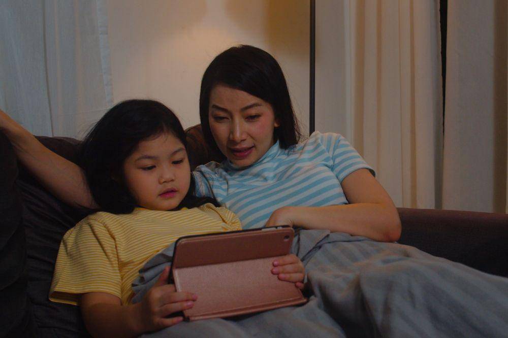 mother relax with little girl watching movie