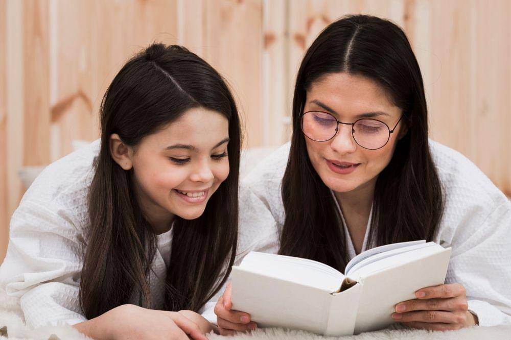 Adult woman reading a book with young girl