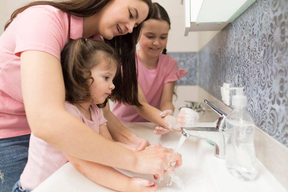 Mother learning girl to wash hands