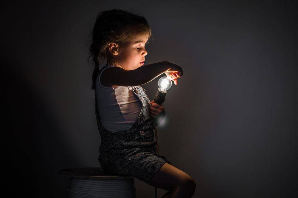 Little cute girl with light bulb in hand