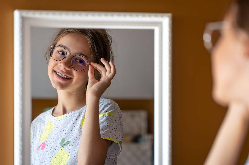 a teenage girl looks at herself in the mirror