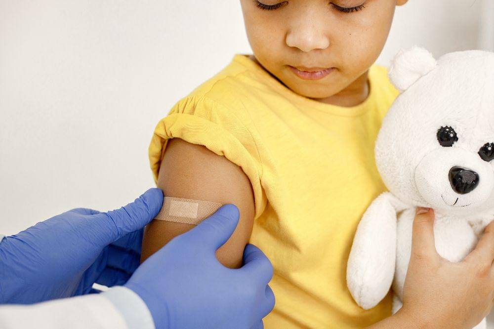 Dokter memberikan plester di bahu anak setelah vaksin