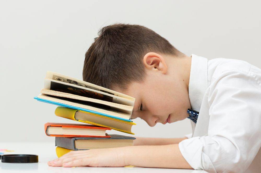Boy sitting with head on books