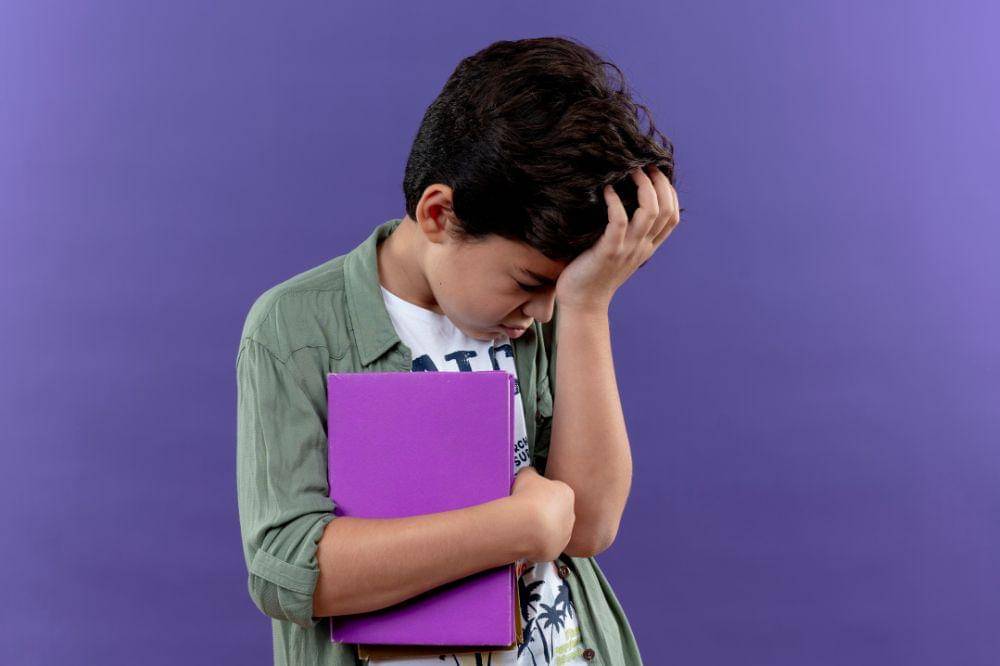 Sad little schoolboy holding book