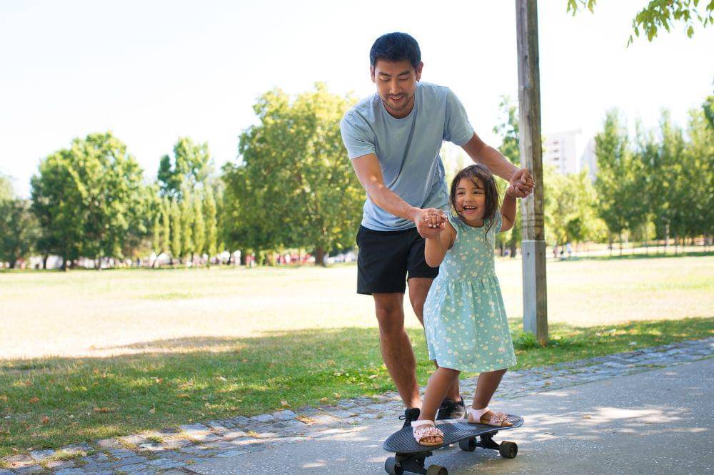 dad and little girl training to skateboard
