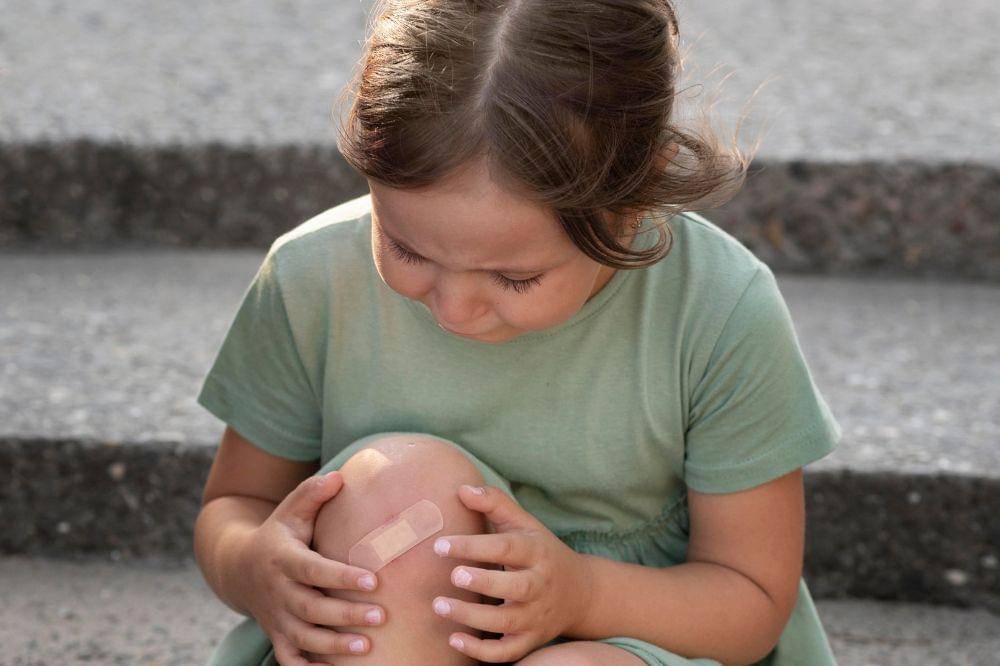 Child looking at her knee injury