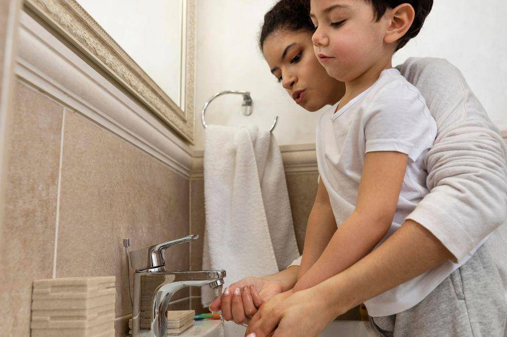 Little boy washing hands with his mom