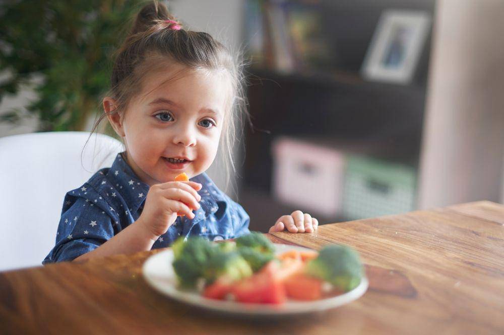 Little girl eating vegetables