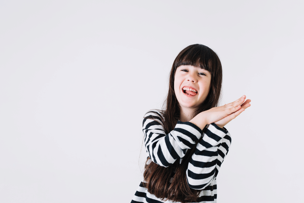 Anak perempuan sedang tertawa sambil menepuk tangannya
