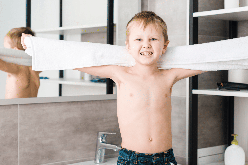 Anak laki-laki sedang memakai handuk di kamar mandi